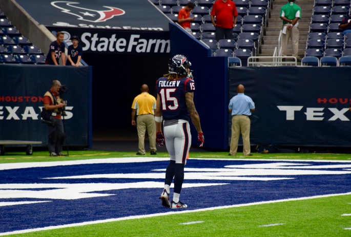 A football player wearing number 15 stands in the endzone.